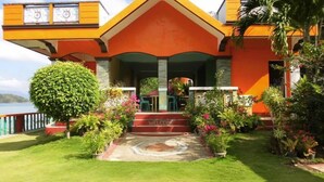 Un edificio colorido con una entrada acogedora, rodeado de exuberante vegetación y vistas al agua.