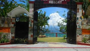 A entrada do Resort El Krimphoff, com vista clara para o oceano e paisagem tropical.