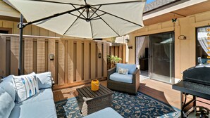 Un patio con sofá, mesa y sombrilla.