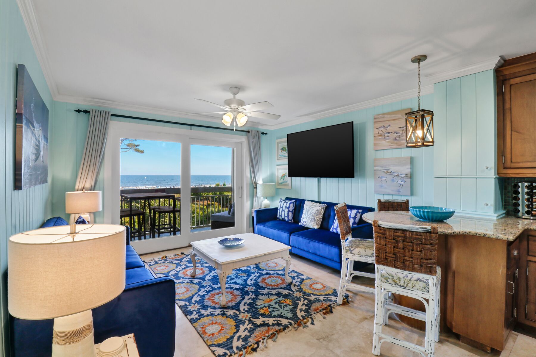 Een woonkamer met een blauwe bank, een salontafel en uitzicht op de oceaan.