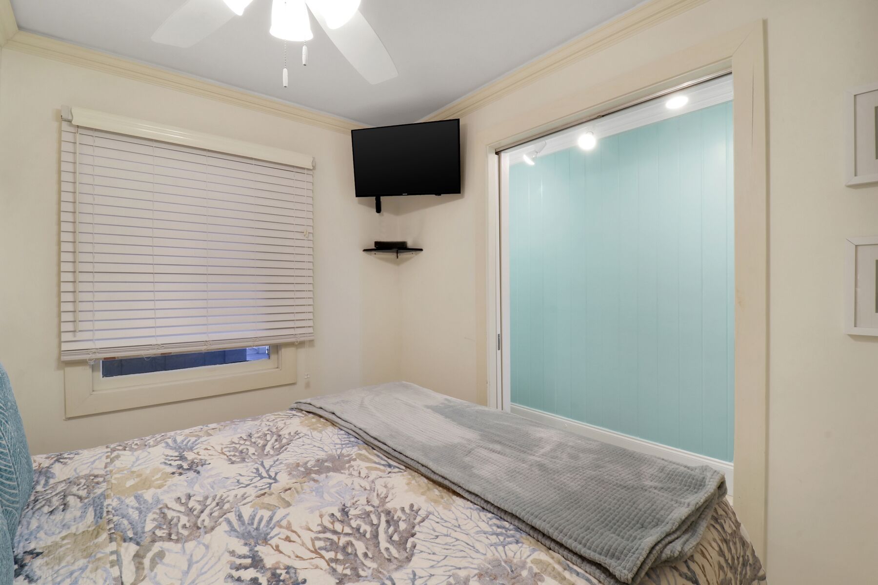 Un dormitorio con una cama, un televisor montado en la pared y un puerta corrediza.