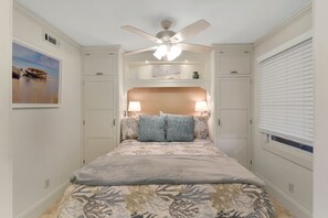 Un dormitorio con cama, ventilador de techo y ventana con persianas.