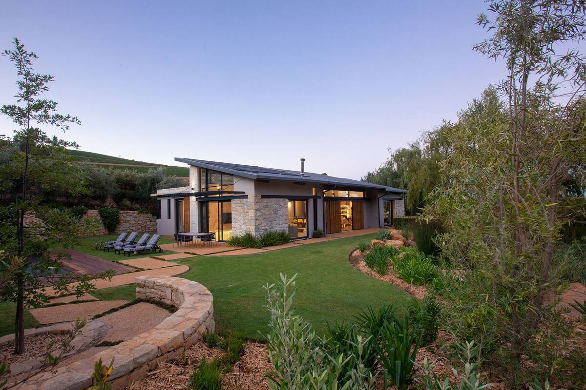 A modern house with a stone facade, large windows, and a well-maintained lawn.