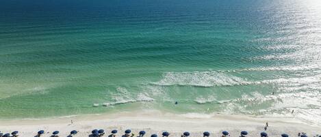 A beach with rows of blue umbrellas and white sand.