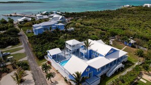 A large resort with multiple buildings, a swimming pool, and a view of the ocean. - Rum & Coconuts-You'll be livin' the Caribbean dream! (Hope Town, Bahamas)