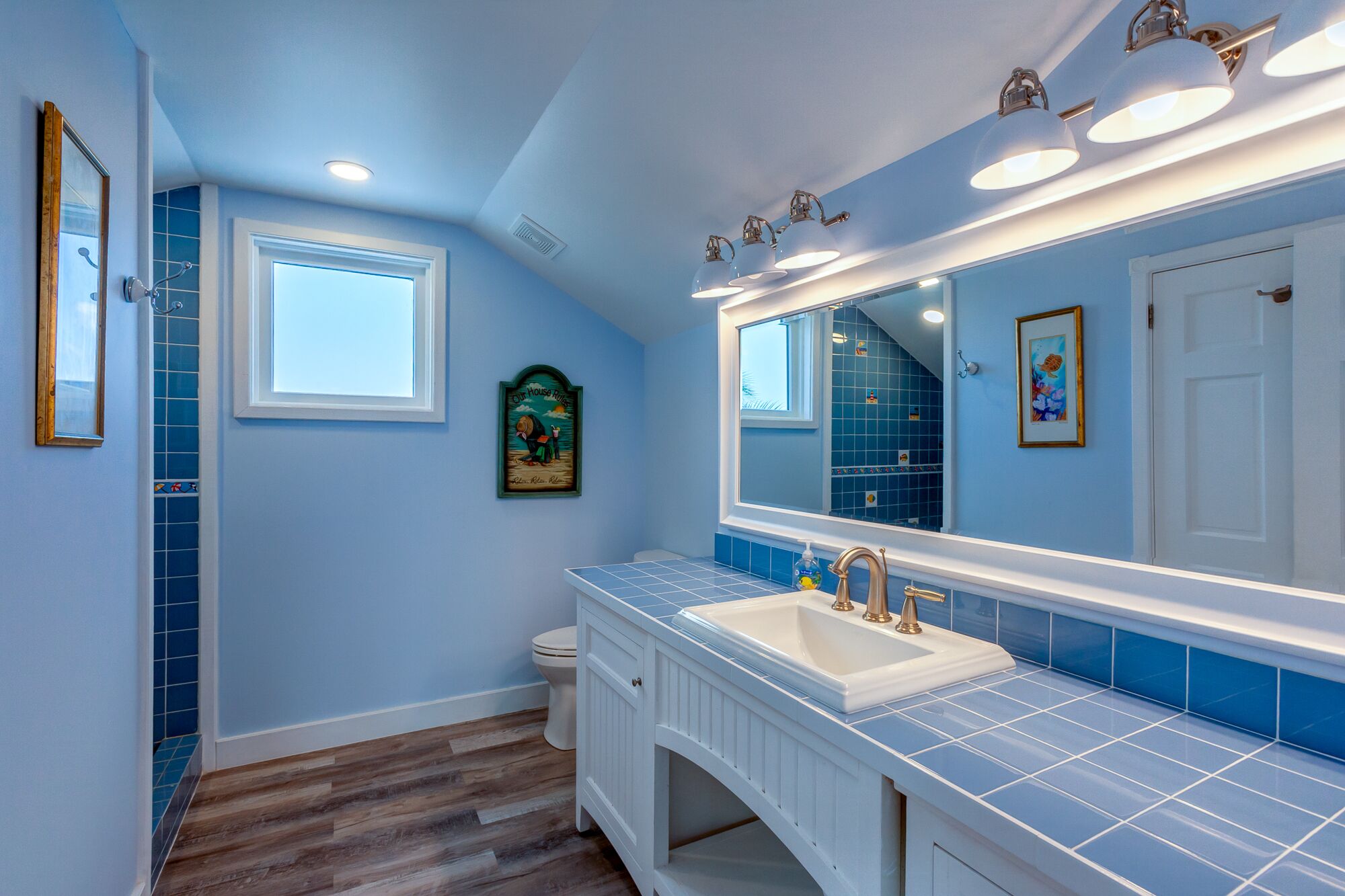 A bathroom with a large mirror, a white sink, and blue tiles.