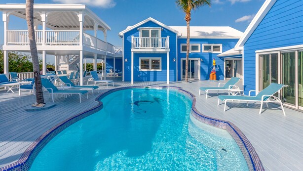 A swimming pool with clear blue water, surrounded by lounge chairs and a deck. - Rum & Coconuts-You'll be livin' the Caribbean dream! (Hope Town, Bahamas)