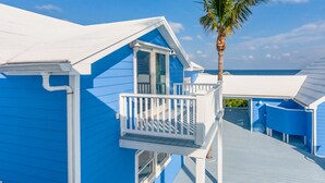 A blue building with a balcony and a palm tree. - Rum & Coconuts-You'll be livin' the Caribbean dream! (Hope Town, Bahamas)