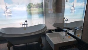 A bathroom with a freestanding bathtub, a sink, and a large mirror. - Fangyuan Hotel (Yantai)