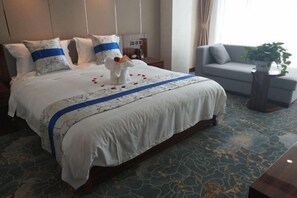 A hotel room with a large bed, a sofa, and a small table.