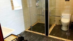 A glass-enclosed shower area with a toilet, a towel rack, and a small shelf with toiletries. - Fangyuan Hotel (Yantai)