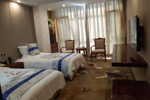 A hotel room with two beds, a TV, a desk, and a chair.