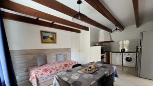 A room with a bed, a dining table with chairs, a kitchen area with a washing machine, and a ceiling fan. - Beautiful T3 for 4/5 people 5 minutes from the beach (Serra-di-Ferro)