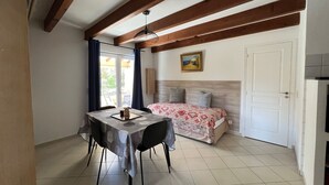 A room with a bed, a table with chairs, a ceiling fan, and a door. - Beautiful T3 for 4/5 people 5 minutes from the beach (Serra-di-Ferro)
