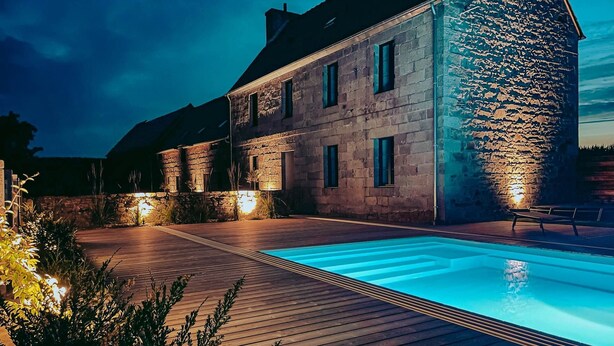 Un edificio in pietra con piscina, terrazza in legno e parete in pietra.
