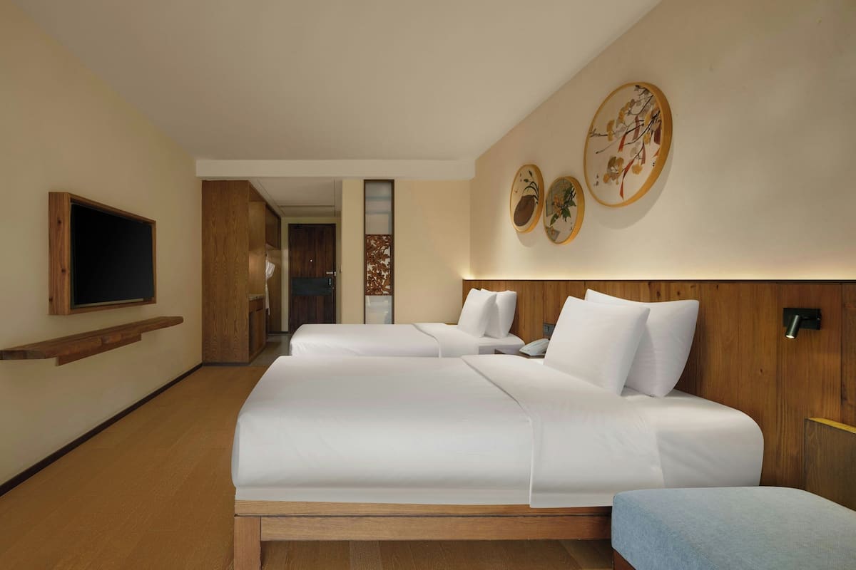 A hotel room with a large bed, a TV mounted on the wall, and wooden paneling.
