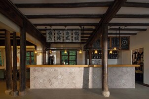 Una zona de bar con techo de madera, faroles colgantes y un muro de azulejos con diseño.