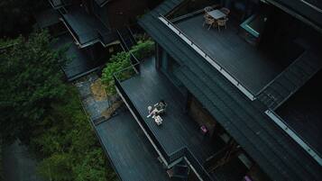 An aerial view of a residential building with a balcony, a small outdoor seating area, and a staircase.