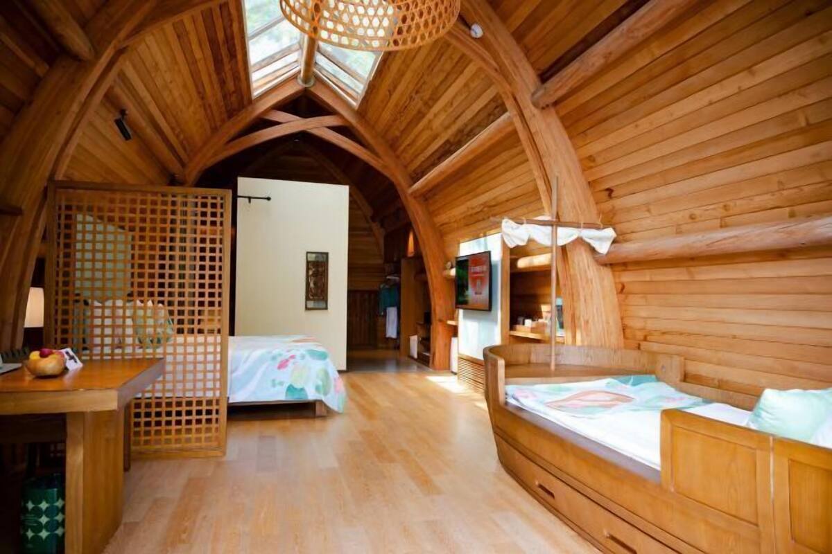 A wooden cabin with two beds, a dining area, and a kitchen.