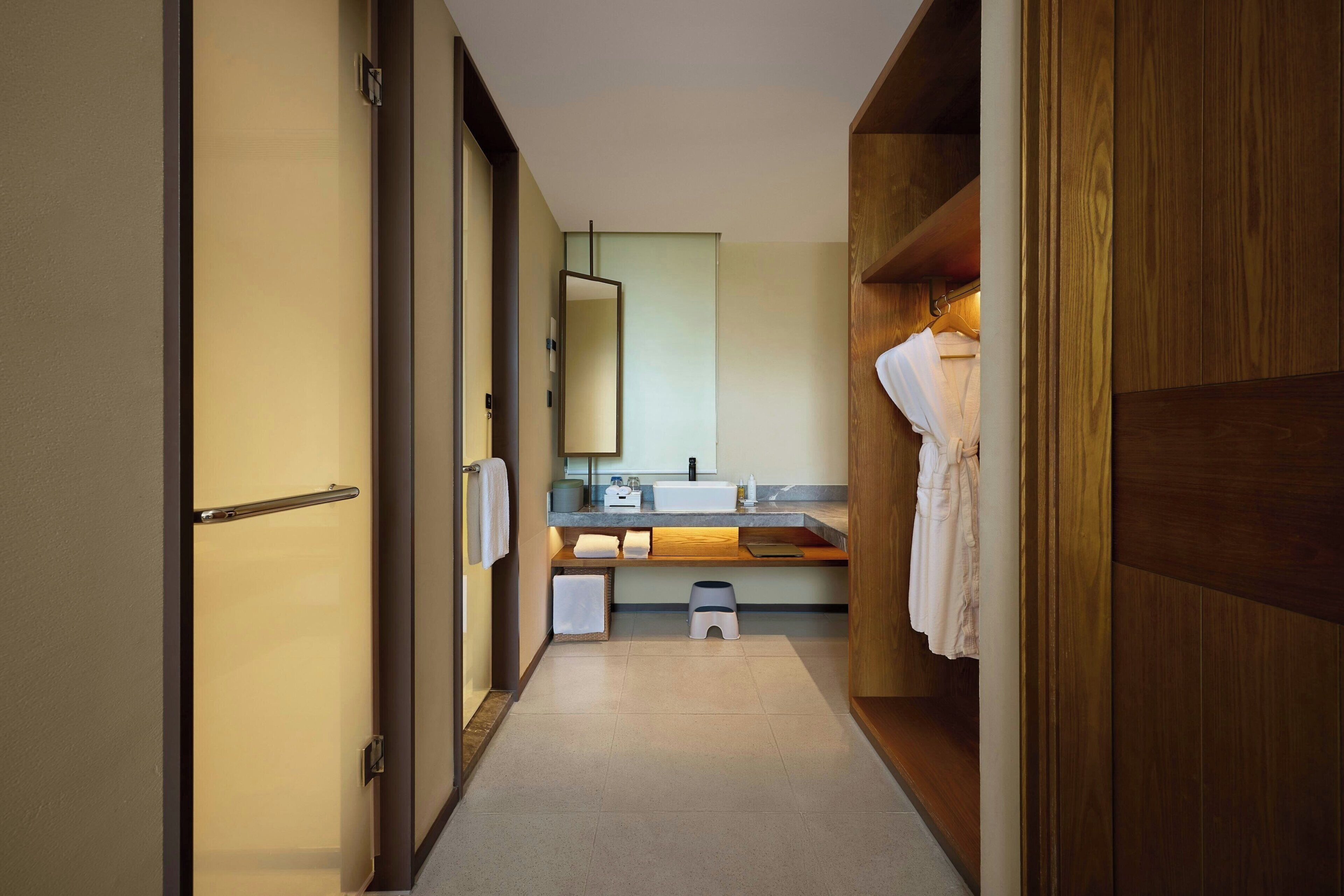 Un baño moderno y estrecho con tocador de madera, un espejo y un perchero.