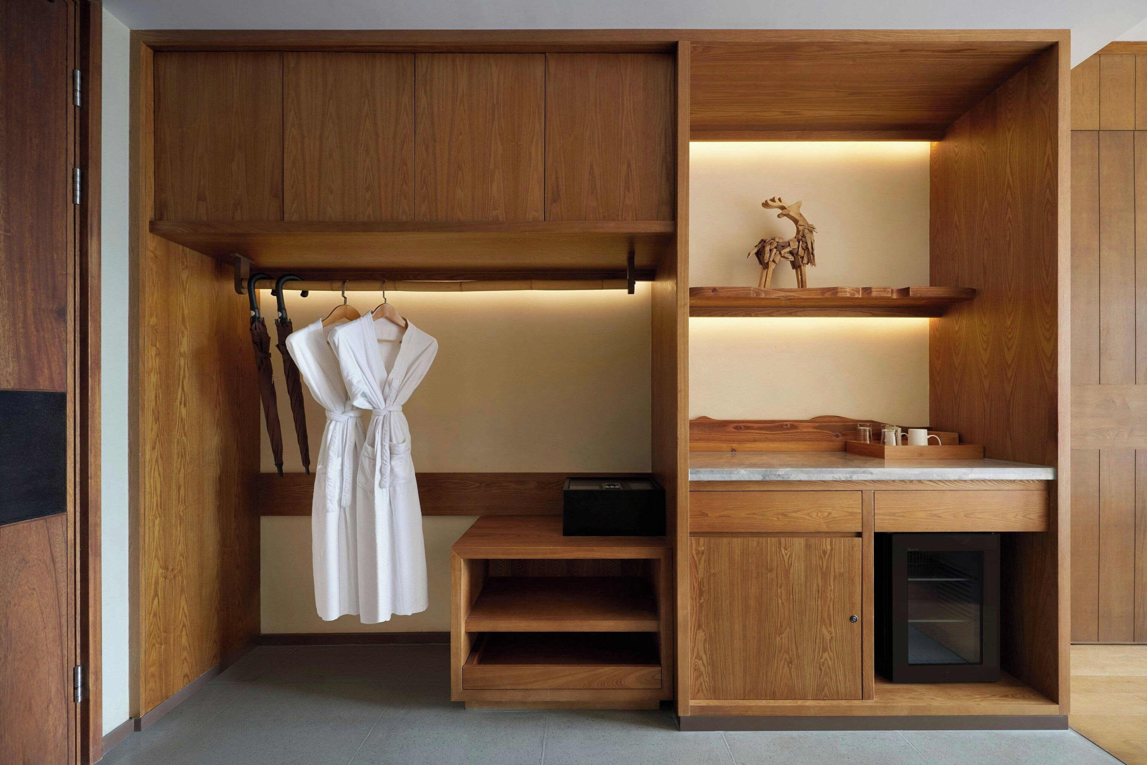 A compact, modern bathroom with wooden cabinetry, a built-in shower, and a towel rack.