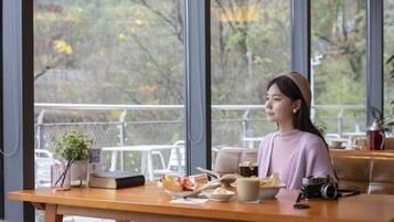 Una persona sentada a una mesa con una computadora portátil, una cámara y comida.