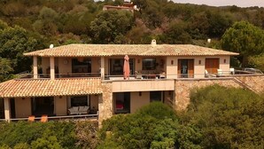 A two-story house with a tiled roof, multiple balconies, and a stone facade. - 5 bedroom house in Palombaggia (Porto Vecchio) with view and direct access to the sea (Porto-Vecchio)