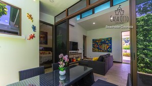 A modern living room with a glass dining table, sofa, and a painting on the wall. - Surf In Surf Out Casa Otto Beachside Colorada (Puntarenas Province)