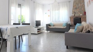 Un salón amplio con comedor, chimenea y una pared de acento de piedra.