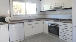 Una cocina con armarios blancos, lavavajillas, estufa y ventana.