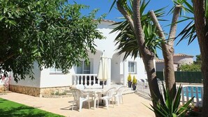 Una villa blanca con un patio, muebles de exterior y piscina.
