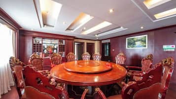 A conference room with a round table, red upholstered chairs, and a large window.
