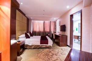 Quarto de hotel com uma cama, uma mesa, uma cadeira, uma televisão e um banheiro visível por uma porta aberta.