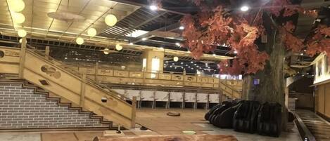 A spacious indoor area with a staircase, a large tree, and luggage storage.