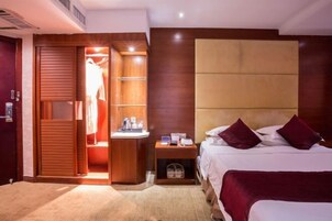 A hotel room with a bed, a nightstand, a wardrobe, and a small seating area.