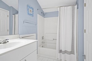 Bathroom features a white bathtub, sink, and vanity with drawers.