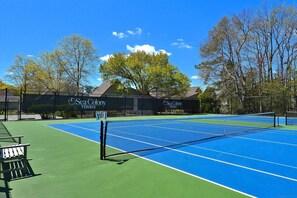 Enjoy tennis on a well-maintained court with clear lines and a net, surrounded by a fence and benches for seating.
