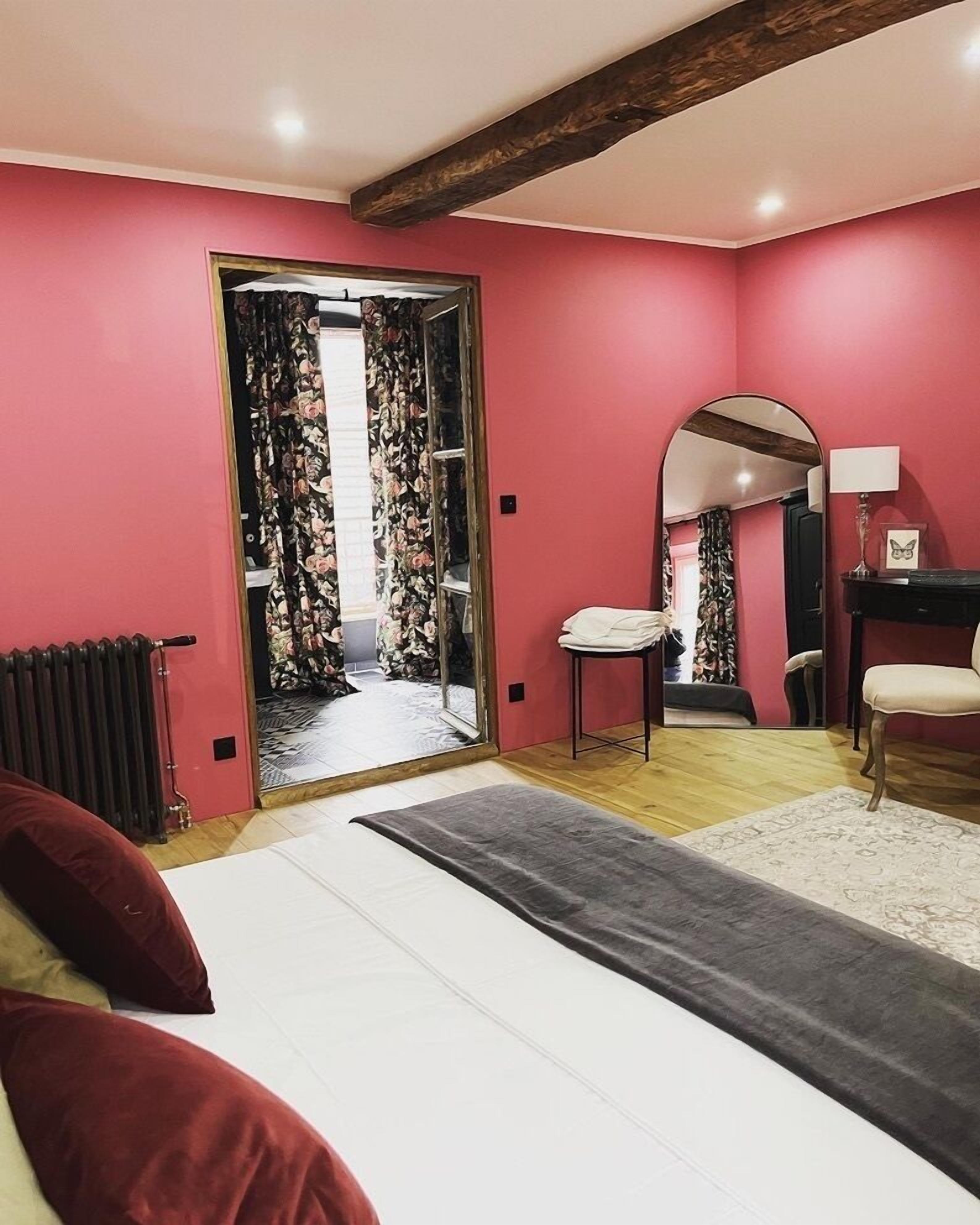 A bedroom with a bed, a radiator, a mirror, and a chair.