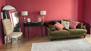 A room with a green sofa, a chair, a small table with lamps, and a mirror on the wall. - Le Fournil de Flavigny The Bakery rooms (Flavigny-sur-Ozerain)