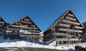 Et hotel med flere altaner, parkeringsplads og sne på jorden.