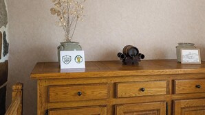 Un aparador de madera con un jarrón de flores secas, un cuadro enmarcado y un certificado encima.