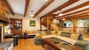 Un salón acogedor con una escalera de madera, una estantería y un sofá con cojines estampados.