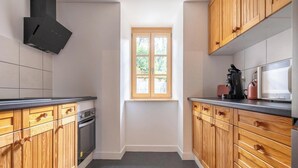 Une cuisine avec des meubles de rangement en bois, une fenêtre et une hotte aspirante noire.