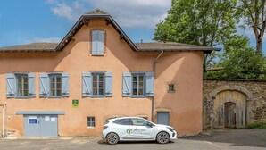 Un immeuble de deux étages avec une voiture garée devant.
