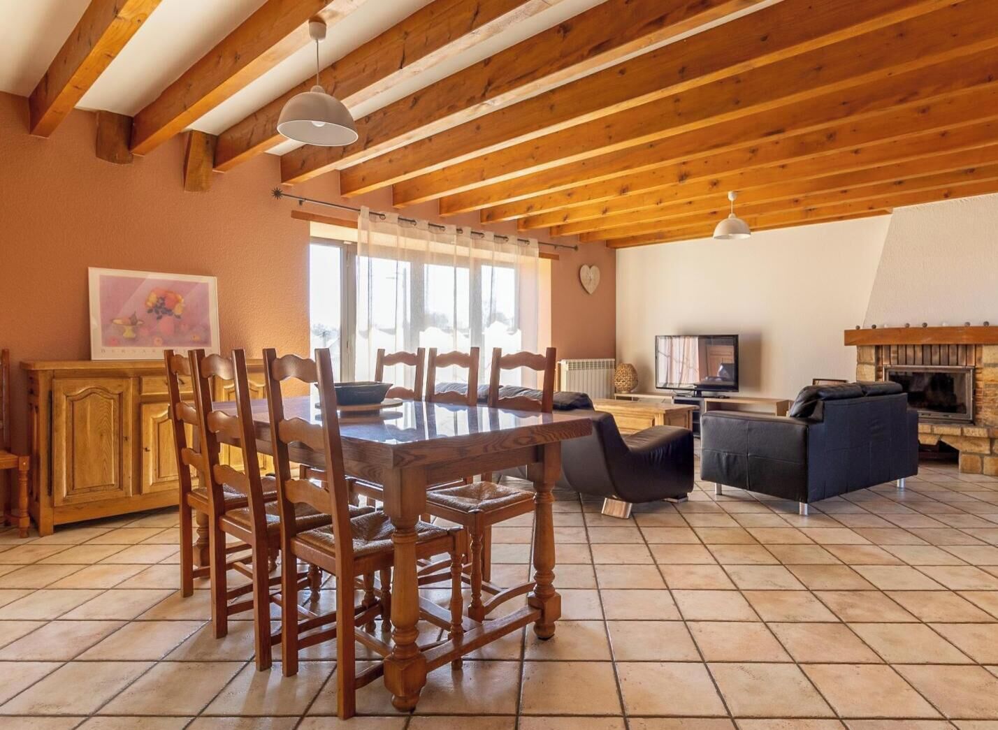 Amplia sala de estar con una mesa de comedor de madera, sillas, un sofá y una chimenea.
