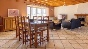 A spacious living area with a wooden dining table, chairs, a sofa, and a fireplace. - Le Balladou - Vernines (VERNINES)