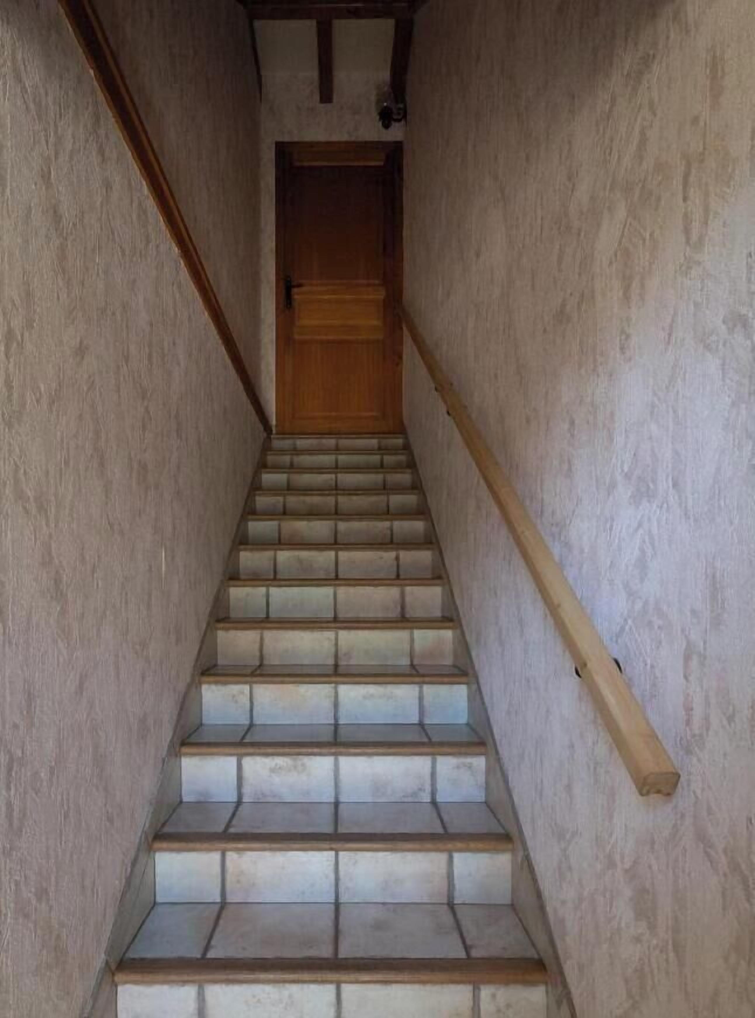 A staircase with wooden handrails and a wooden door at the top.