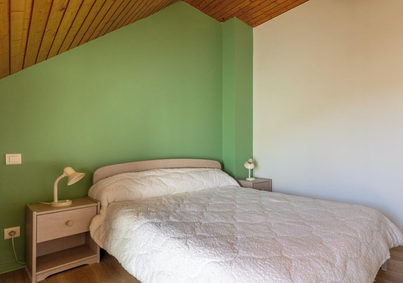 Ein Schlafzimmer mit einem Bett, zwei Nachttischen und einer Lampe auf jedem Tisch.