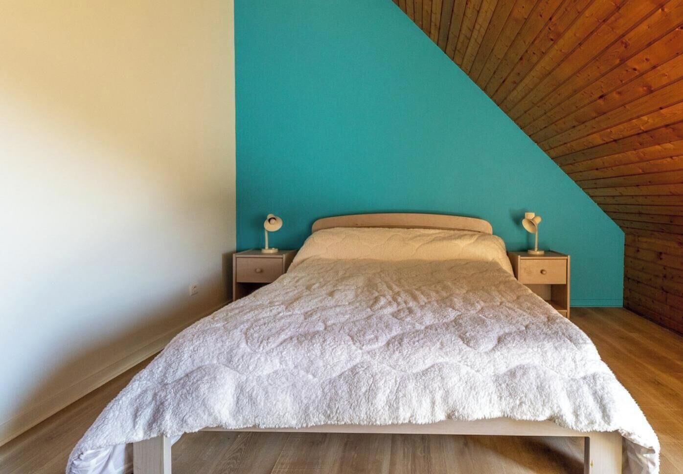A bedroom with a bed, two bedside tables, and a sloped ceiling.