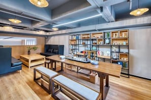 A modern interior with a wooden dining table, benches, a bookshelf, and a seating area.